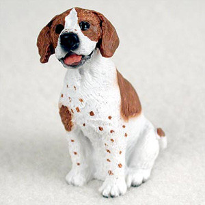 A detailed miniature figurine of a brown and white Pointer dog sitting in an upright, attentive pose. The dog features floppy reddish-brown ears, a matching patch on its back, and delicate brown ticking spots across its white chest and front legs. With its mouth slightly open and a pink tongue visible, the figurine has a happy and friendly expression, complemented by its dark, shiny eyes. This small, hand-painted figure is designed as a charming decorative accessory to be placed at the base of a bonsai tree or within a miniature garden.