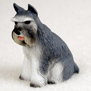 A detailed miniature figurine of a salt-and-pepper Schnauzer dog sitting on a neutral, off-white background. This gray and white bonsai tree accessory captures the classic breed traits, including a bushy white beard, prominent white eyebrows, and alert, pointed ears. The figurine's textured finish mimics a coarse coat of fur, featuring a dark gray back and head with stark white legs and chest. A small pink tongue peeks out from its mouth, adding a touch of personality to this small-scale garden decor piece.