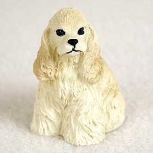 A detailed miniature figurine of a blonde Cocker Spaniel dog, sitting in an upright position. The small statue features the breed's characteristic long, wavy ears and a textured coat sculpted to mimic fur in a cream-blonde shade. It has small, distinct black eyes and a nose. This figurine is intended as a decorative accessory for bonsai tree displays or fairy gardens, adding a charming and personalized touch to miniature landscapes.