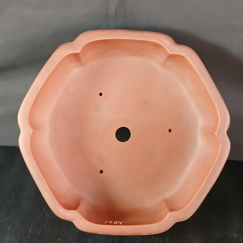 A top-down view of a 13-inch round Yixing bonsai pot, item number 1784, showcasing its interior and distinctive shape. The pot is crafted from a smooth, matte, unglazed clay in a traditional reddish-brown terracotta hue. Its rim features an elegant scalloped or lobed design, giving the round pot a floral-like profile from above. In the center of the deep basin is a large drainage hole, surrounded by three smaller, purposefully placed wire holes used for securing a bonsai tree with wire. Near the bottom interior edge, the item number "1784" is delicately inscribed in white. The pot is set against a simple, dark, neutral background that highlights its warm clay tones and architectural form.