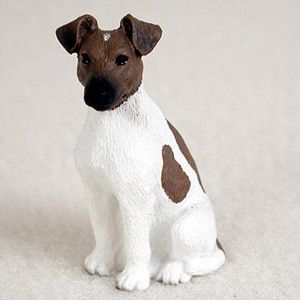 A detailed miniature figurine of a brown and white Smooth Fox Terrier, designed as a decorative bonsai tree accessory. The small dog statue is depicted in a sitting pose, facing slightly to the left with an alert expression. It features a primarily white body with a realistic molded fur texture, accented by a solid brown head with a black muzzle and dark eyes, and a distinctive brown patch on its left flank. This lifelike Fox Terrier figurine is shown against a neutral, light-colored background, highlighting its intricate hand-painted details and its suitability as a charming addition to a miniature garden or bonsai display.