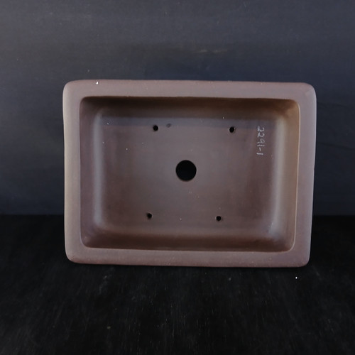A top-down, overhead view of a 12-inch unglazed Yixing bonsai pot, crafted from deep chocolate brown clay with a smooth matte finish. The rectangular pot features soft, rounded corners and a thick rim. Inside the basin, a large central drainage hole is visible, flanked by four smaller wiring holes positioned in the corners for securing a tree. The serial number "2291-1" is stamped in white on the interior right wall. The pot is centered against a dark, minimalist background that emphasizes its clean lines and functional design.