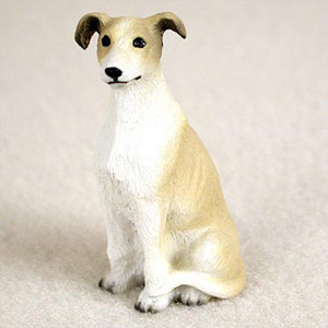 A small, detailed figurine of a tan and white Greyhound or Whippet, designed as a decorative accessory for a bonsai tree or miniature garden. The dog is depicted in a graceful sitting position, with its front legs straight and its tail neatly curled toward its hindquarters. 

The figurine features a realistic coat pattern, with soft tan patches covering the ears, the top of its head, and the length of its back and sides, while the chest, face, and legs are a clean white. Its face is finely crafted with expressive dark eyes, a small black nose, and characteristic rose-shaped ears that fold slightly forward. 

The surface of the figurine has a subtle, carved texture to mimic the appearance of short fur. Set against a neutral, softly textured beige background, this miniature canine statue is intended to bring a sense of scale, life, and personality to a bonsai display or terrarium landscape.