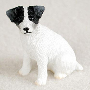 A detailed bonsai tree figurine of a Jack Russell Terrier, specifically designed with a black and white color pattern and a textured "rough coat." The small dog figurine is depicted in a seated position, looking directly forward with an alert expression. It features solid black patches over its ears and surrounding its eyes, while the rest of its body is a crisp white. The surface of the figurine is intricately molded with fine lines and ridges to simulate the coarse, wiry fur typical of a rough-coat Jack Russell. This miniature dog accessory is intended for placement at the base of a bonsai tree, adding a touch of realism and personality to a miniature indoor garden landscape.
