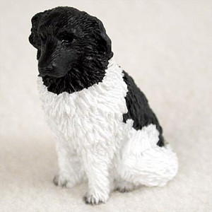 A detailed miniature figurine of a Landseer dog, designed as a decorative accessory for a bonsai tree or miniature garden. The figurine depicts a sitting dog with the breed's characteristic markings: a solid black head and ears, a stark white neck, chest, and front legs, and a black patch over its back. The surface of the figurine is intricately sculpted with a heavy texture to realistically mimic the thick, shaggy, and wavy coat of a Newfoundland dog. The miniature animal is shown in an alert, upright sitting pose against a neutral, soft beige background, highlighting its hand-painted details and small scale.