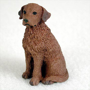 A detailed miniature figurine of a Chesapeake Bay Retriever, specifically designed as a decorative accent for a bonsai tree or miniature garden. The figurine is shown in a sitting position, looking slightly to the left with an attentive expression. It features a realistic, textured, liver-brown coat that captures the breed's characteristic thick and wavy fur. This small, hand-painted collectible is crafted from durable cast stone or resin, making it a perfect addition to any outdoor or indoor bonsai arrangement. The figurine is set against a simple, soft white background that highlights its intricate craftsmanship.