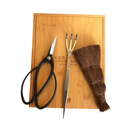 Tinyroots shear, broom and rake kit laid out on a bamboo board