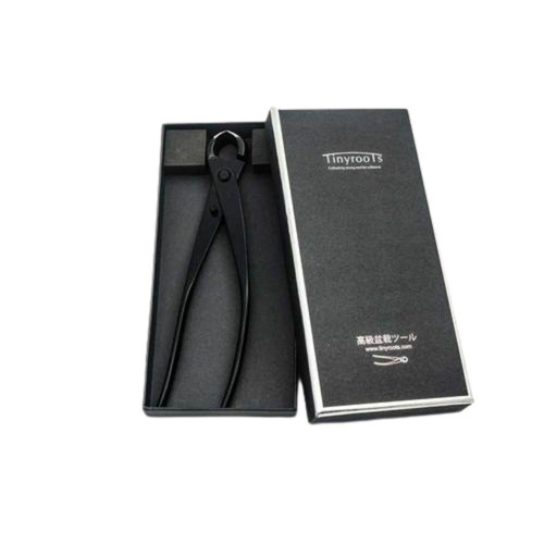A product image of Tinyroots carbon steel root and knob cutters, a specialized advanced bonsai tool, presented in its professional black storage box. The matte black tool features long handles and distinctive cutting blades shaped like two halves of a sphere, designed to leave a slightly concave cut that heals cleanly. The tool rests in a form-fitting foam insert within an open black box. To the right, the box's lid is visible, displaying the Tinyroots brand name and Japanese characters for "high-grade bonsai tool." The minimalist presentation against a stark white background highlights the precision engineering of this essential bonsai pruning instrument.