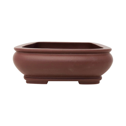 A side-profile photograph of a rectangular Yixing bonsai pot, crafted from unglazed, deep reddish-brown clay with a smooth, matte finish. The pot features an elegant "bag-shaped" design where the sides curve outward from the top before tapering back in towards the base. It has a flat top rim with a subtle horizontal ridge running just below it. The rectangular pot has softly rounded corners and sits elevated on four small, blocky feet at each corner. The interior of the pot matches the dark earthen color of the exterior, and the entire object is presented against a clean, white background, emphasizing its classic form and texture.
