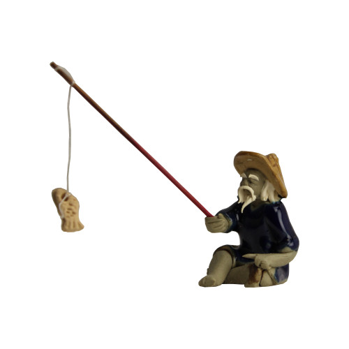 A traditional Chinese "mud man" ceramic figurine designed as a miniature bonsai decoration. The figurine depicts an elderly fisherman sitting in a relaxed pose, wearing a wide-brimmed, conical straw-colored hat and a glossy, deep blue glazed tunic. He has a long, flowing white mustache and beard made of unglazed clay.

The fisherman holds a long, thin red fishing rod that extends upward and outward. A white string line hangs from the tip of the rod, with a small, unglazed tan ceramic fish dangling at the end. The man’s face, hands, and bare feet feature a natural, matte ceramic finish, a hallmark of traditional Shiwan pottery. This serene miniature is designed to add a sense of scale, life, and storytelling to a penjing or bonsai tree display.