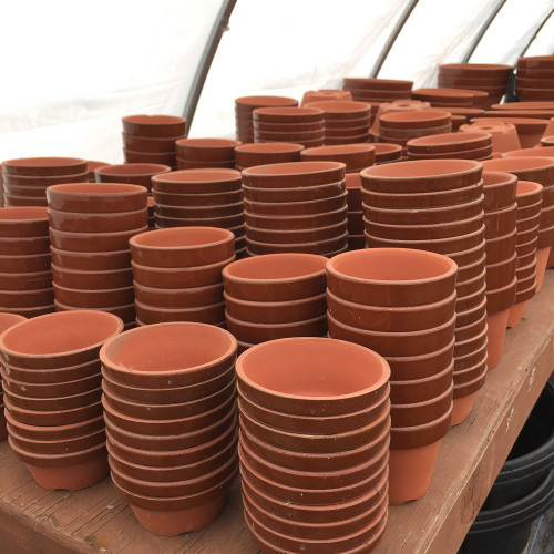 Stacks of unglazed Japanese Tokoname training pots on a wooden bench