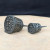 Two dark gray mesh bonsai fertilizer cups, medium and small, on a stone surface