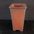 A 6-inch tall, unglazed Yixing ceramic bonsai pot designed in a classic cascade style. This deep, rectangular pot tapers slightly from top to bottom and features a warm, reddish-brown terracotta color with a smooth, matte finish. It has a prominent wide rim around the upper opening and four small, integrated block feet at the base for stability and drainage. Set against a dark, minimalist background, the pot's clean lines and earthy texture are clearly visible, showcasing its suitability for trailing bonsai trees.