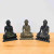 Three handmade Buddha statues seated on lotus thrones, arranged on a wood surface
