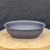 Charcoal grey oval plastic training pot on a natural wood slab