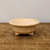 Round cream glazed bonsai pot on a weathered wooden tabletop