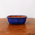 Rectangular blue glazed bonsai pot on a textured brown wooden surface