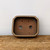 Top-down view of the brown glazed bonsai pot on a rustic surface