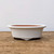 Shallow oval white glazed bonsai pot on a weathered wooden tabletop