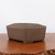 A detailed studio photograph captures a set of three nesting unglazed brown bonsai pots, stacked from largest to smallest. These ceramic pots feature a classic rectangular "cushion" shape with subtly bowed sides and indented corners, providing a soft yet structured aesthetic. 

The pots are crafted from smooth, matte-finished clay in a warm, earthy chocolate-brown tone. Small, integrated feet at the base of each pot provide slight elevation for drainage and airflow. The set is displayed on a polished, rich dark wood surface that shows a natural, rustic live edge in the bottom foreground. The background is a clean, neutral off-white, which highlights the simple lines and natural texture of the bonsai containers. This set of unglazed pots is ideal for traditional bonsai styles, offering a timeless and understated look that complements a wide variety of tree species.