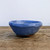 Rustic glazed bowl-shaped pot on a weathered wooden surface