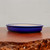 A side-profile view of an elegant, shallow oval bonsai pot featuring a rich and vibrant cobalt blue glaze. The ceramic pot is displayed on a polished, dark mahogany-colored wooden table with a rugged, naturally textured front edge. The background is a clean, neutral-toned wall, which allows the bold color and smooth, glazed finish of the pot to stand out. This classic blue glazed bonsai pot's sleek design is a perfect choice for various bonsai tree styles and is an essential accessory for any enthusiast looking for a high-quality ceramic container.