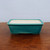 Rectangular teal glazed pot on a dark polished wooden surface