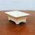 Three quarter view of the cream glazed pot on dark textured wood