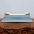 Side view of the rectangular light blue glazed pot on a burl stand