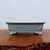 Rectangular light blue glazed pot on a dark polished wood surface