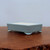 Rectangular light blue glazed pot on a polished dark wood surface