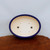 Oval royal blue glazed pot on a natural-edge polished wood surface