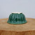 Underside of the small green glazed pot on a wooden block