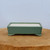 Rectangular matte sage green pot on a rustic wooden cross-section