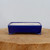 A detailed, straight-on view of a rectangular, vibrant cobalt blue glazed bonsai pot from Bonsai Outlet. The pot features smooth, rounded corners and sits elevated on four small, flared feet. The exterior has a deep, glossy blue glaze, while the interior is a contrasting light cream color with subtle blue speckling. The container is centered on a natural, rustic wood slice pedestal against a clean, light gray wall, showcasing its elegant and minimalist design for displaying a bonsai tree.