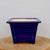 Square cobalt blue glazed pot on a light-colored wooden round