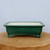 Rectangular forest green glazed pot on a rustic wooden log slice