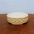 Shallow round pot in speckled cream glaze on dark polished wood