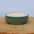 Shallow round glazed pot on a light-colored wooden surface