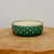 Shallow round forest green pot on a thick natural wooden base