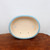 Top-down view of the oval light blue pot on dark brown wood