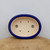 Top-down view of the oval pot with a cobalt rim and beige interior
