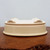 Underside of the cream glazed pot on a dark textured wood surface