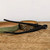 A pair of professional Tinyroots black carbon steel concave branch cutters rests across two handcrafted ceramic bonsai pots on a weathered wooden surface. The pot on the left is a shallow, round dish with a speckled sage green glaze and a natural tan interior. Beside it, the second pot features a heavily textured, carved exterior with green and brown glazes. The matte black bonsai tool, with the "Tinyroots" brand name visible on the handle, is part of a high-quality carbon steel tool kit designed for precise bonsai maintenance. The background is a clean, minimalist off-white, emphasizing the artistic and functional nature of the bonsai starter kit items.