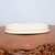 The shallow cream pot tipped to show its base and foot ring