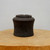 Unglazed charcoal grey ceramic pot on a natural wood pedestal