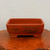 Rectangular unglazed terracotta pot on a polished wood surface