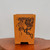 Tall rectangular unglazed pot in warm orange-buff clay on burl wood