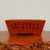 Rectangular unglazed pot with flared sides in smooth reddish orange clay
