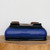 A detailed view of a nine-inch Yixing bonsai pot, shown upside down on a natural wooden slab against a plain white background. The ceramic pot features a striking, deep cobalt blue glaze with a slightly mottled finish. Its shape is a softly rounded rectangle with elegant, outward-curving sides. The pot's underside reveals the natural, unglazed reddish-brown Yixing clay, featuring four rectangular feet at each corner and a large circular drainage hole in the center. A thin, dark blue-black line accents the transition from the glazed body to the base and the top rim, adding a touch of sophisticated contrast.